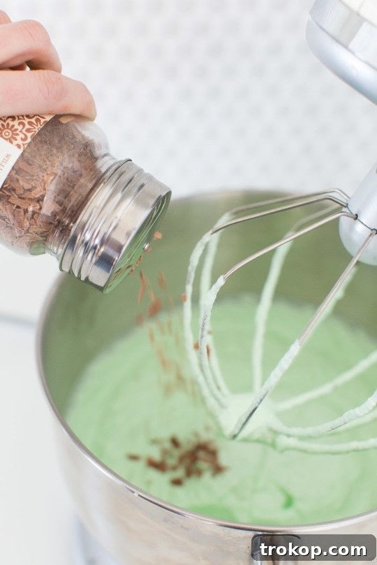 Ingredients for Creme de Menthe ice cream laid out: heavy cream, sweetened condensed milk, chocolate shavings, and a bottle of Creme de Menthe.