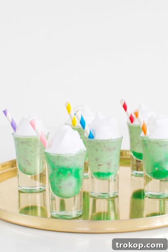 Crème de Menthe Ice Cream Shots served in elegant shot glasses, adorned with a mint sprig, against a festive backdrop.