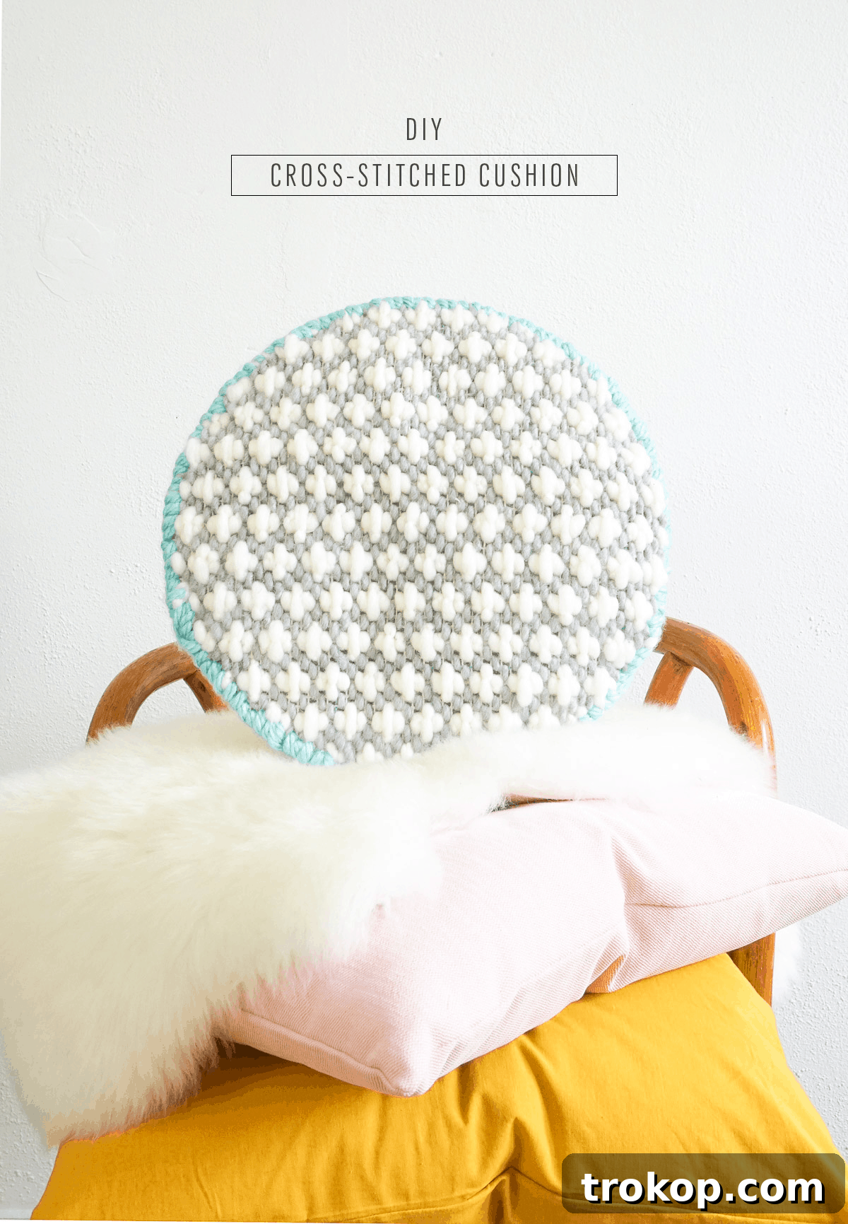 Artisan Oversized Cross-Stitch Pillow 13 A stylish living space featuring the oversized cross-stitched cushion on a rattan chair, complementing a vibrant, modern aesthetic.
