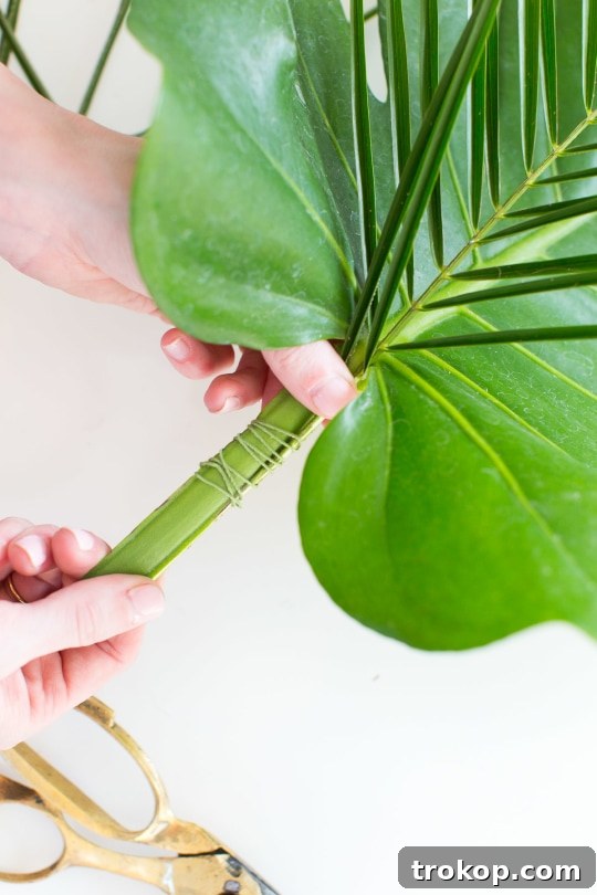 Beginning the DIY floral bar cart swag by layering palm leaves