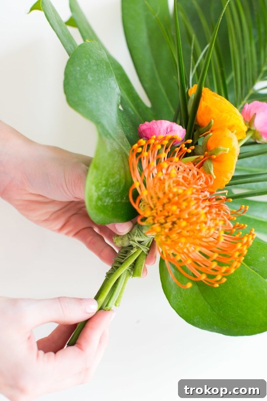 Adding first layer of flowers like ranunculus to the palm leaf base