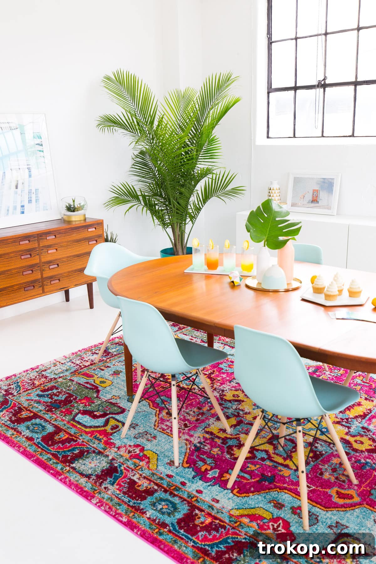 Modern dining room setup with blue chairs and colorful rug for summer entertaining