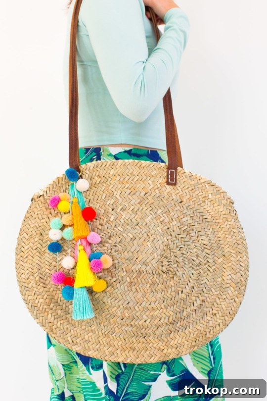 Detail shot of the colorful pom poms and tassels adorning a stylish circle beach bag, ready for summer adventures.