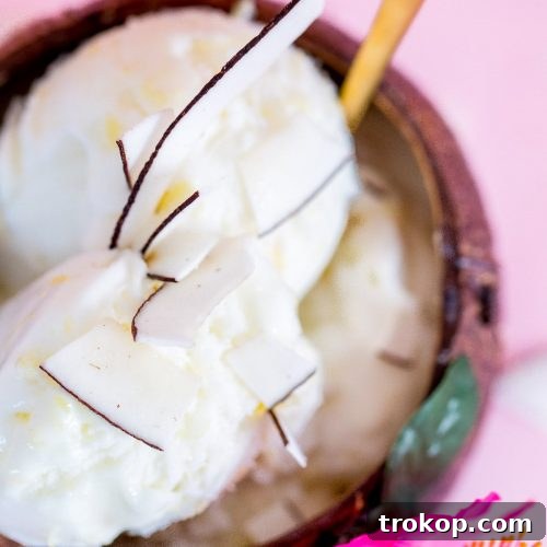 A vibrant scoop of No-Churn Creamy Pineapple Coconut Ice Cream in a bowl, garnished with coconut flakes.