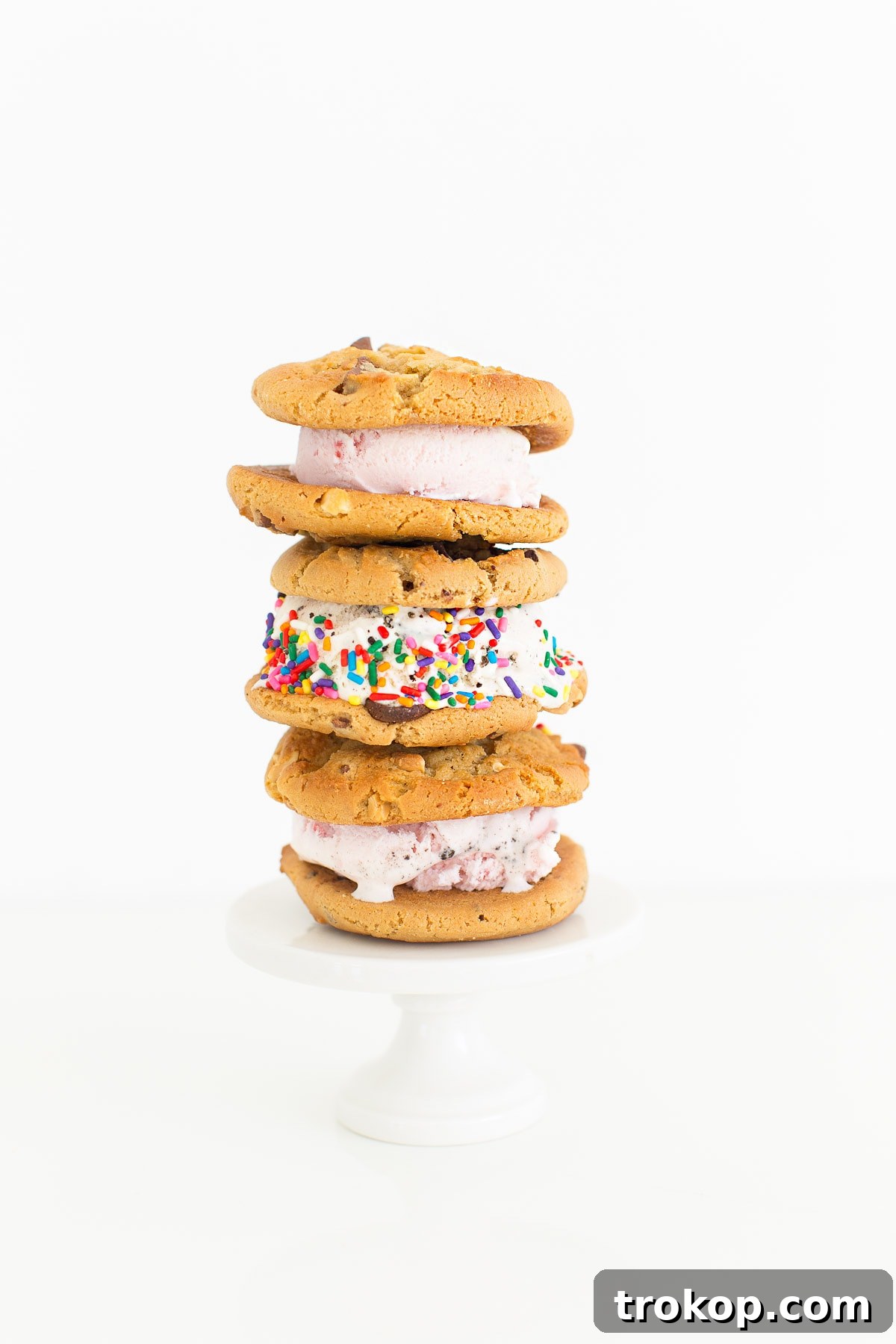 A hand holding a Baskin-Robbins warm cookie ice cream sandwich against a bright, sunny backdrop, epitomizing summer joy.