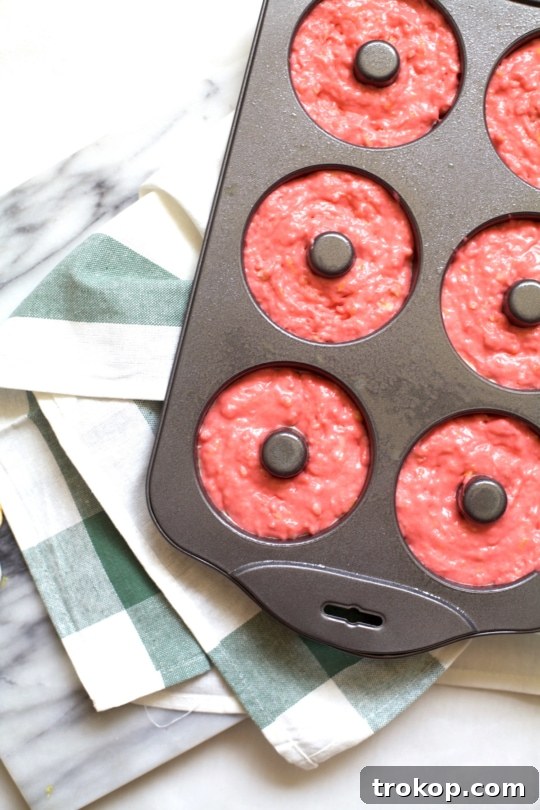 Freshly baked pink lemonade donuts cooling on a wire rack