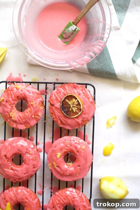 Pink lemonade donuts being dipped in a vibrant pink glaze