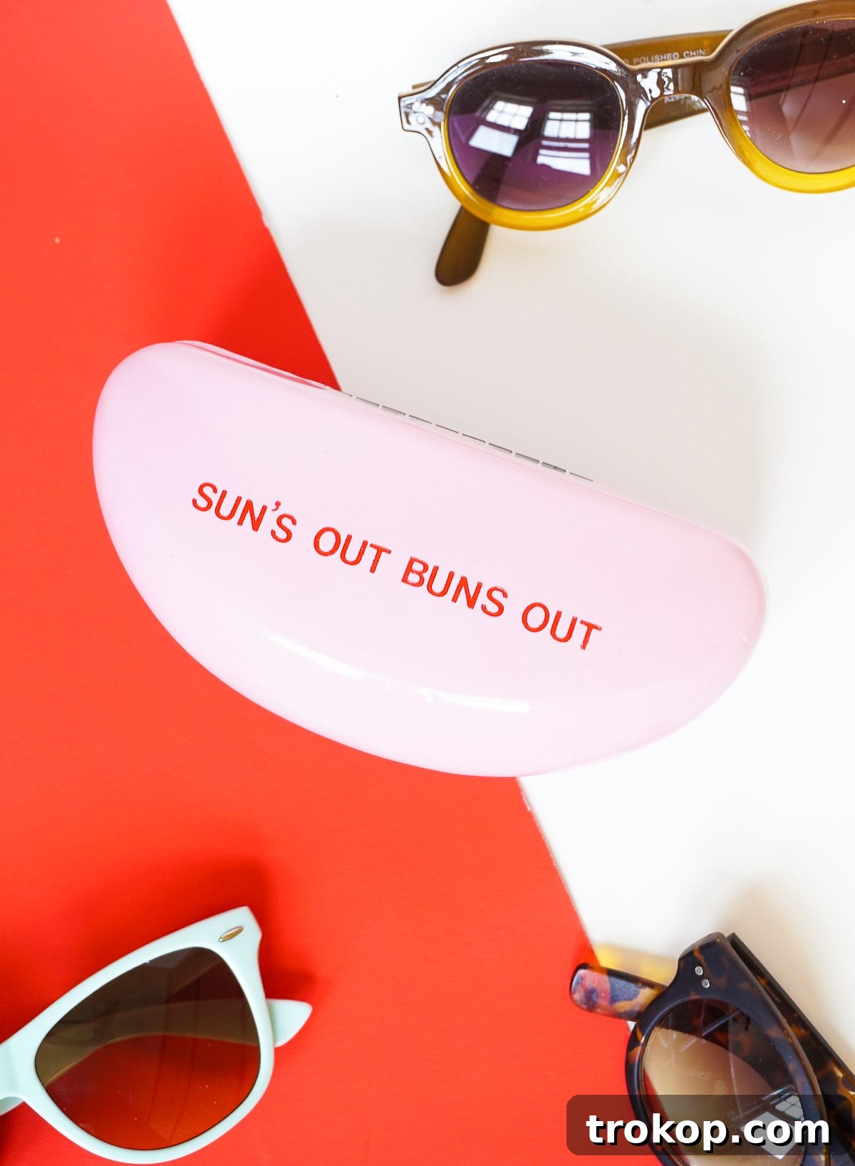Close-up of the 'Sun's Out Buns Out' phrase being applied to the retro sunglasses case.
