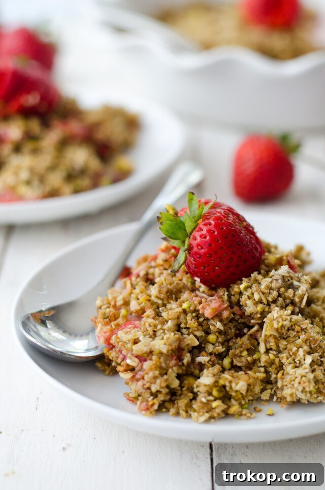 Heavenly Strawberry Pistachio Crumble 7 A baked Pistachio Strawberry Crumble in a baking dish, with a spoon ready for serving.