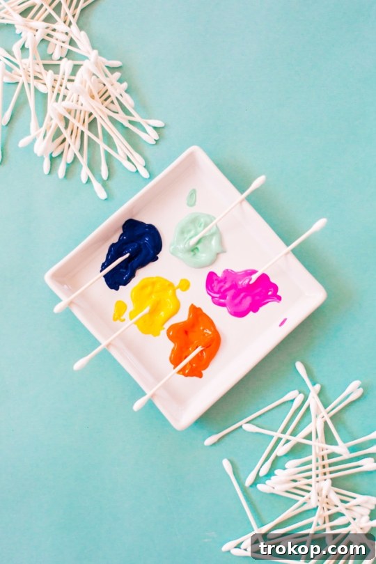 Collection of materials laid out for DIY confetti pattern placemats: Q-tips, craft paints, and blank placemats, ready for a creative session - sugar and cloth