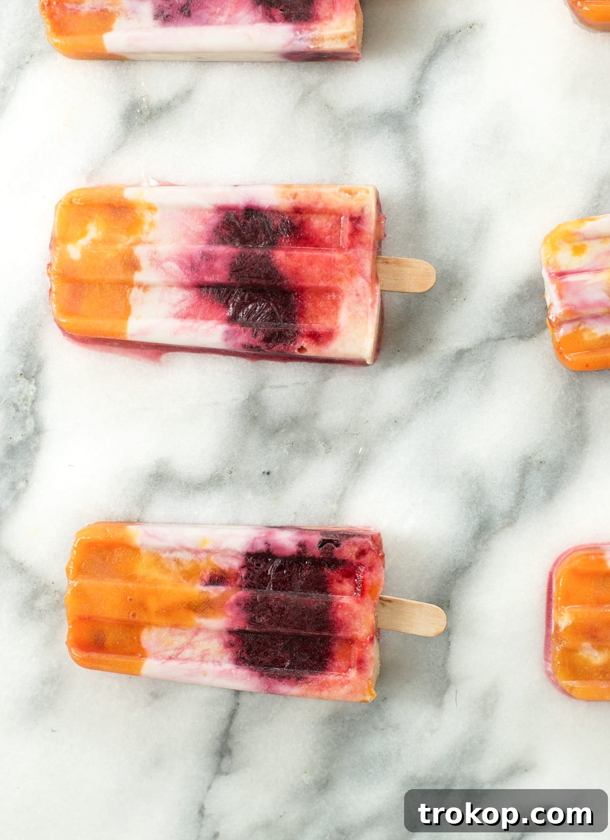 Beautifully layered Roasted Peach and Cherry Popsicles captured in a close-up, highlighting their vibrant colors and appealing texture