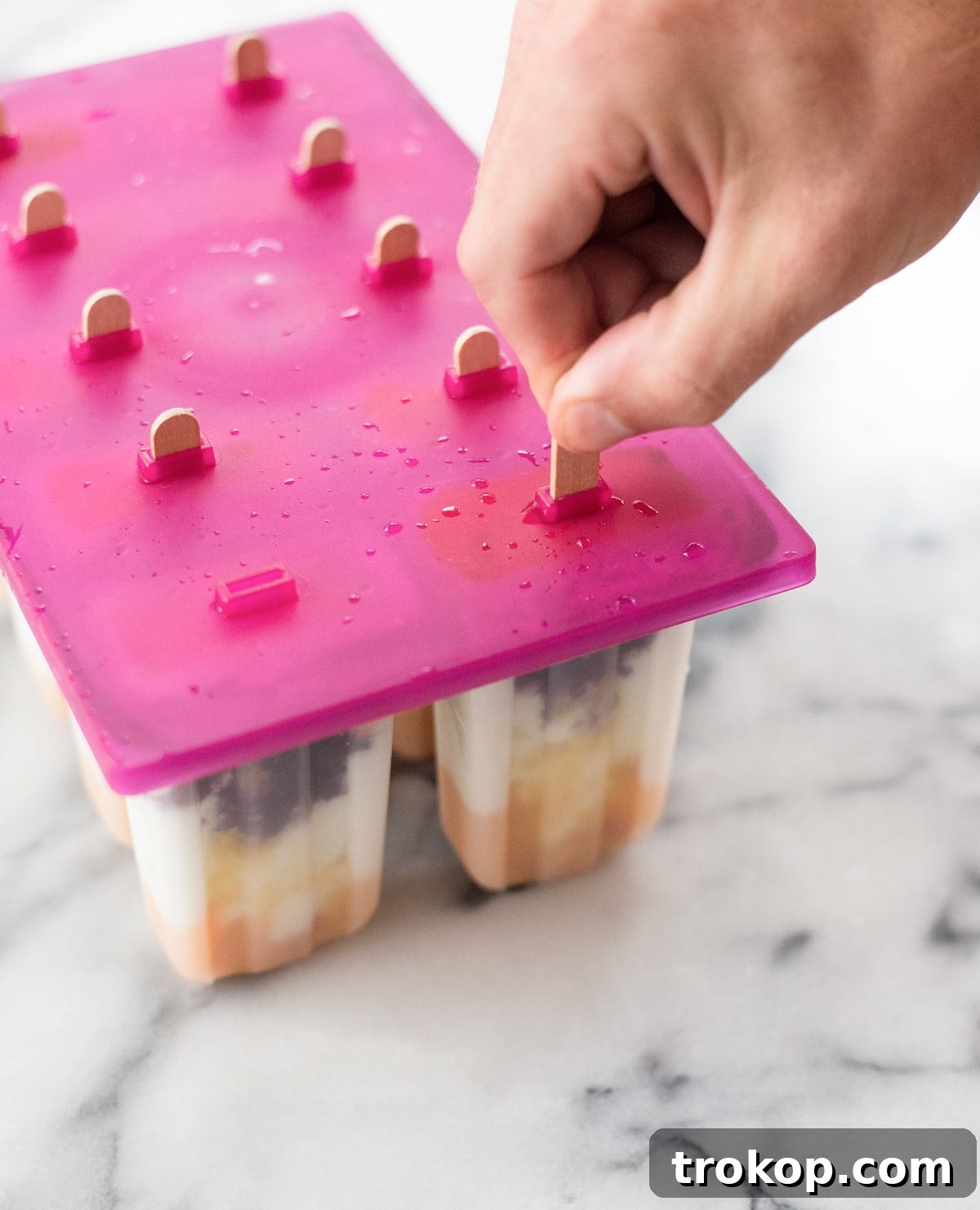 A single, perfectly frozen Roasted Peach and Cherry Popsicle, highlighting its layers and refreshing appeal
