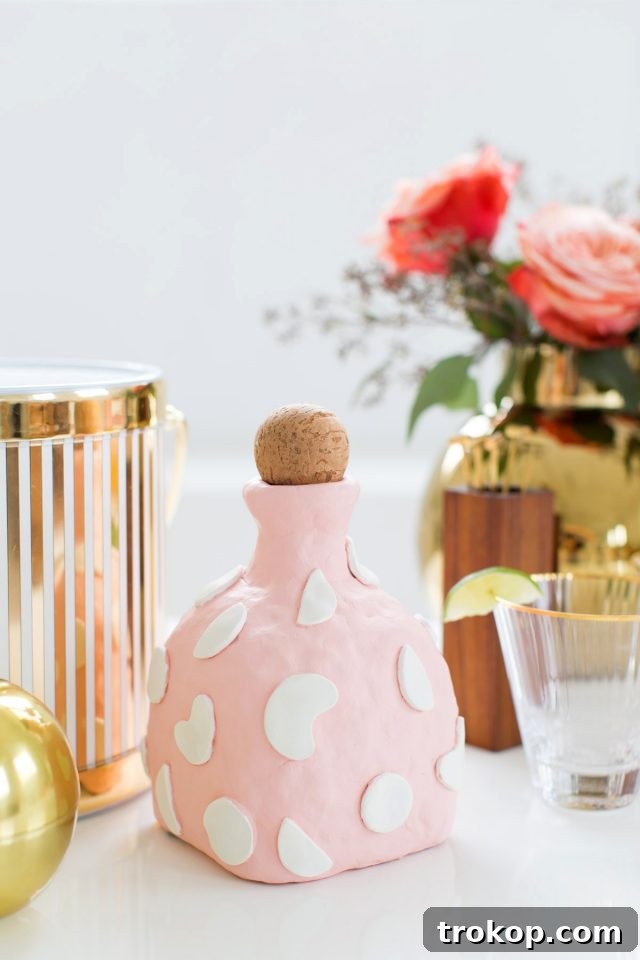 Close-up view of an air-dry clay decanter, highlighting its rustic texture and the original glass bottle peeking through the clay application.
