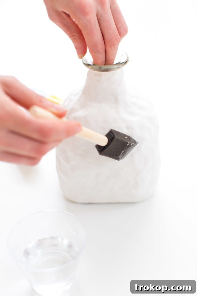 Detailed view of the bottom edge of the clay-covered bottle, showing a neat and even line where the clay meets the glass base.