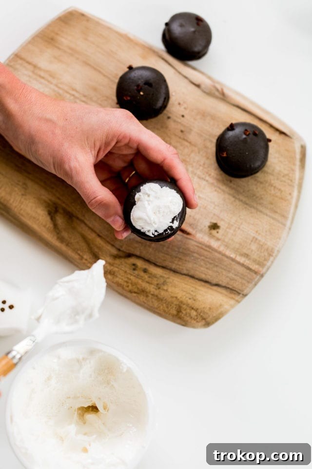 Applying Marshmallow Fluff to Macarons for Ghost Toppers