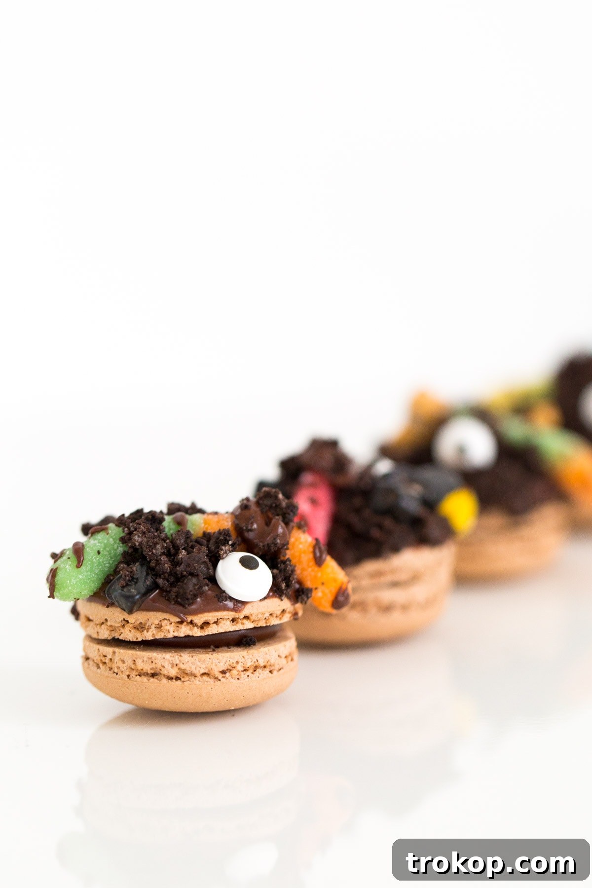 A close-up of multiple DIY Dirt Worm Macarons arranged for a Halloween party.
