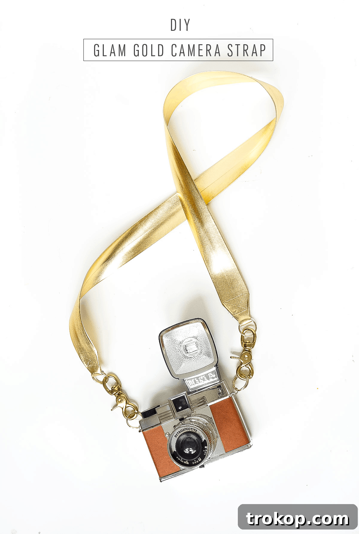 Close-up of the elegant metallic gold DIY Glam Camera Strap wrapped around a photographer's hand, ready for use.