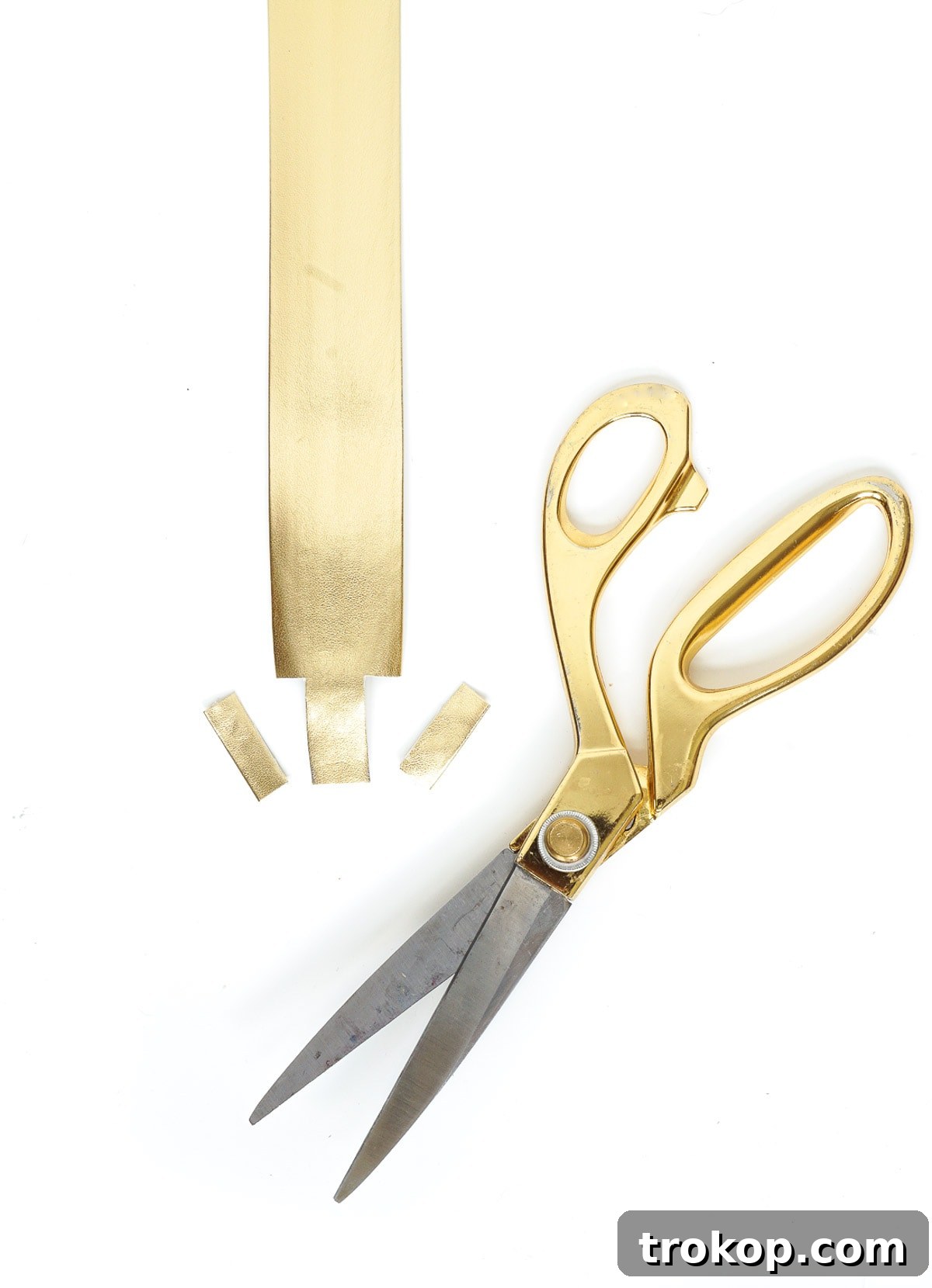 Gathered materials for DIY Glam Camera Strap: metallic gold belting trim, clasps, rings, gold thread, sewing machine, scissors, and double-sided tape.