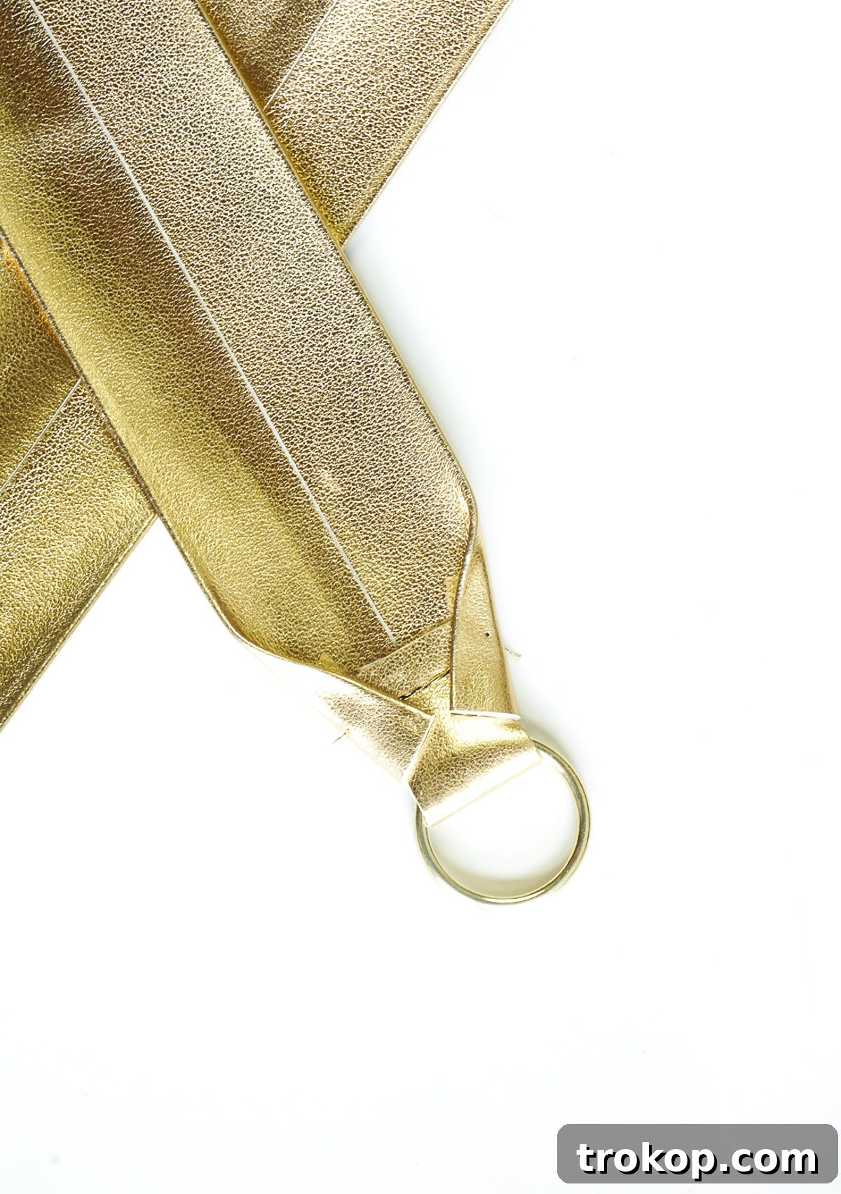 Close-up of the sewing machine stitching a horizontal line with gold thread across the folded end of the DIY camera strap, above the split ring.