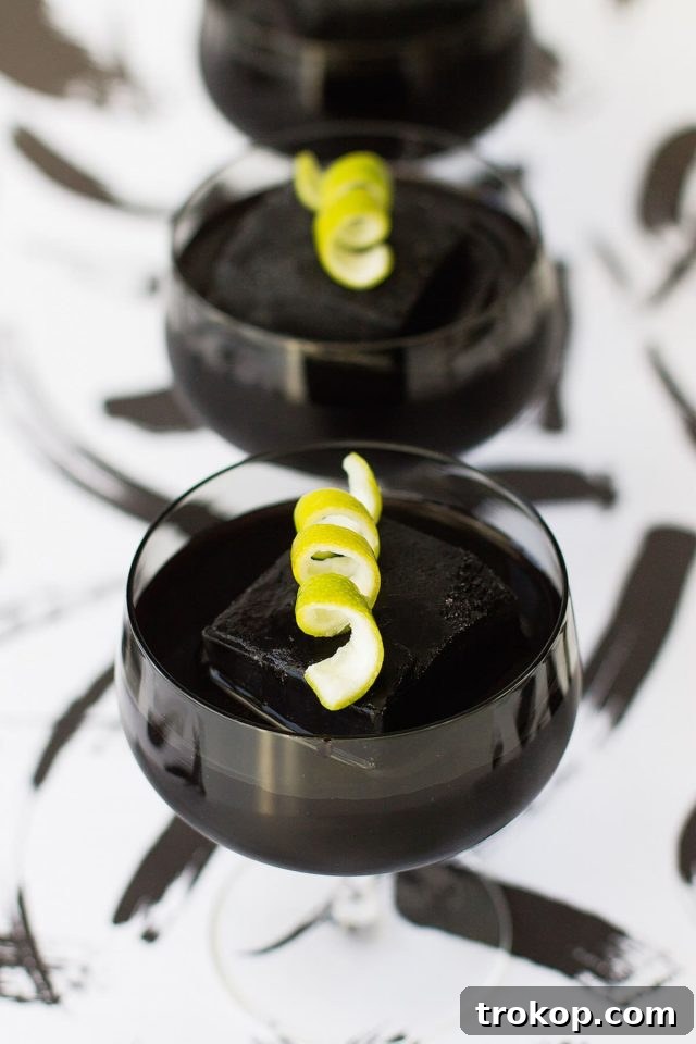 Activated Charcoal Elixirs: Detox Cocktails and Mocktails 2 A perfectly dark and mysterious Halloween-themed activated charcoal cocktail garnished with a vibrant lime curl, ideal for detoxification and refreshment.