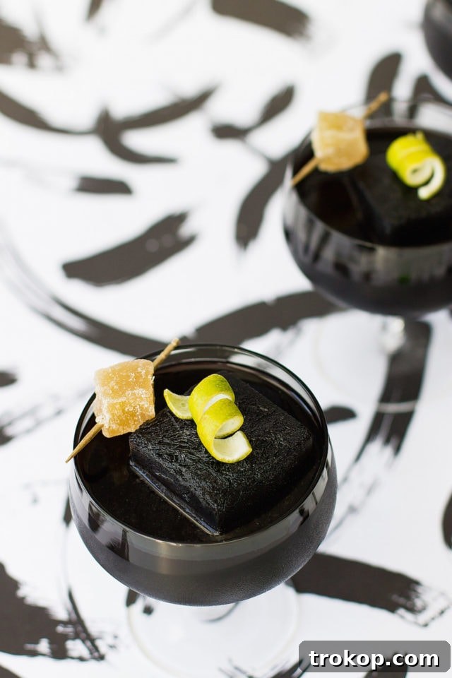 Activated Charcoal Elixirs: Detox Cocktails and Mocktails 8 A close-up of an activated charcoal cocktail, elegantly garnished with a fresh lime slice and a piece of candied ginger, showcasing its sophisticated presentation.