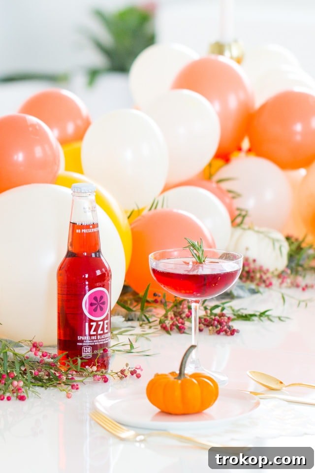 Beautifully decorated Friendsgiving table with a balloon centerpiece and a Blackberry Blitz cocktail