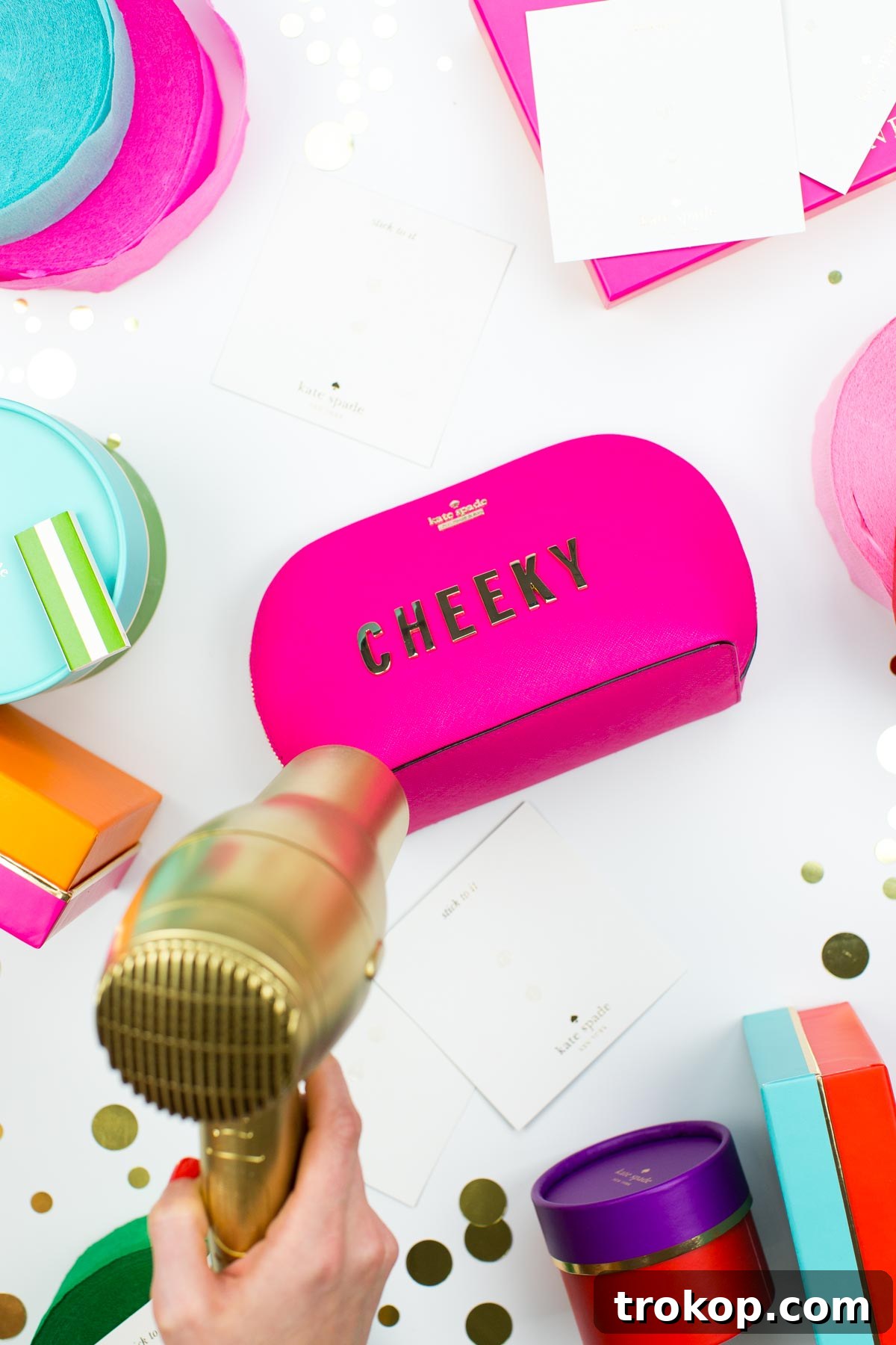A close-up of a personalized Kate Spade pouch featuring gold adhesive letters on a colorful background.