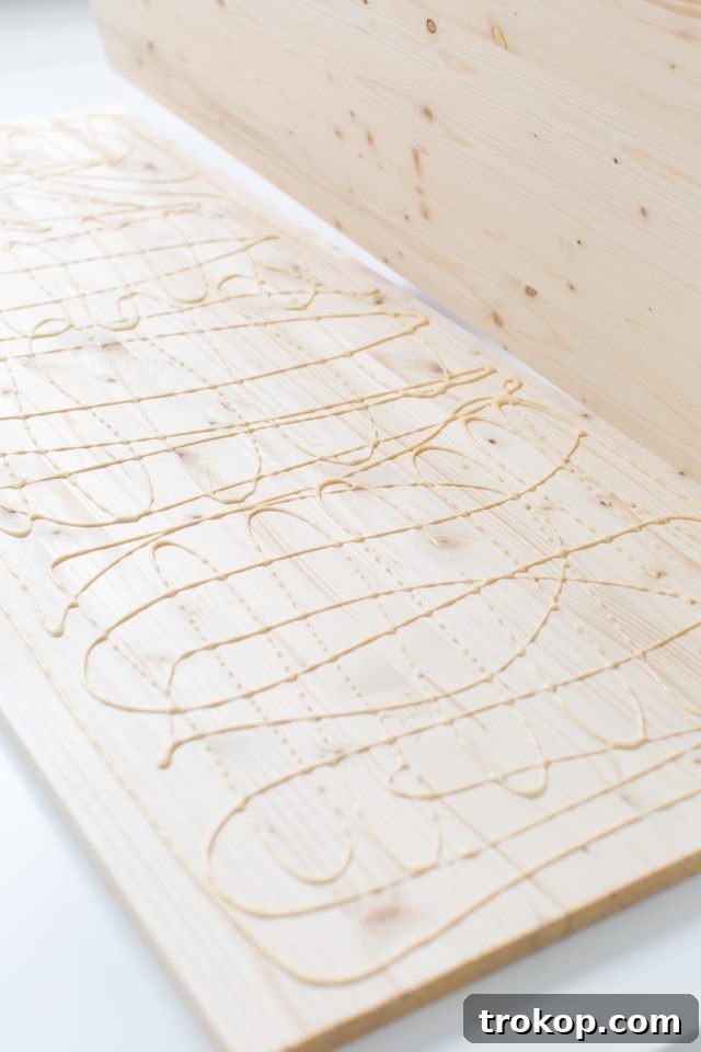 Applying wood glue to join two pre-cut wood boards, the first step in creating a sturdy modern low bench.