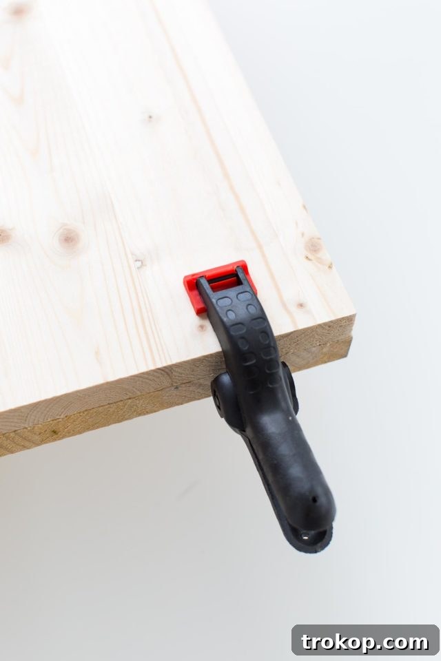 Wood boards clamped together, drying after glue application to form the robust top of the DIY modern low bench.
