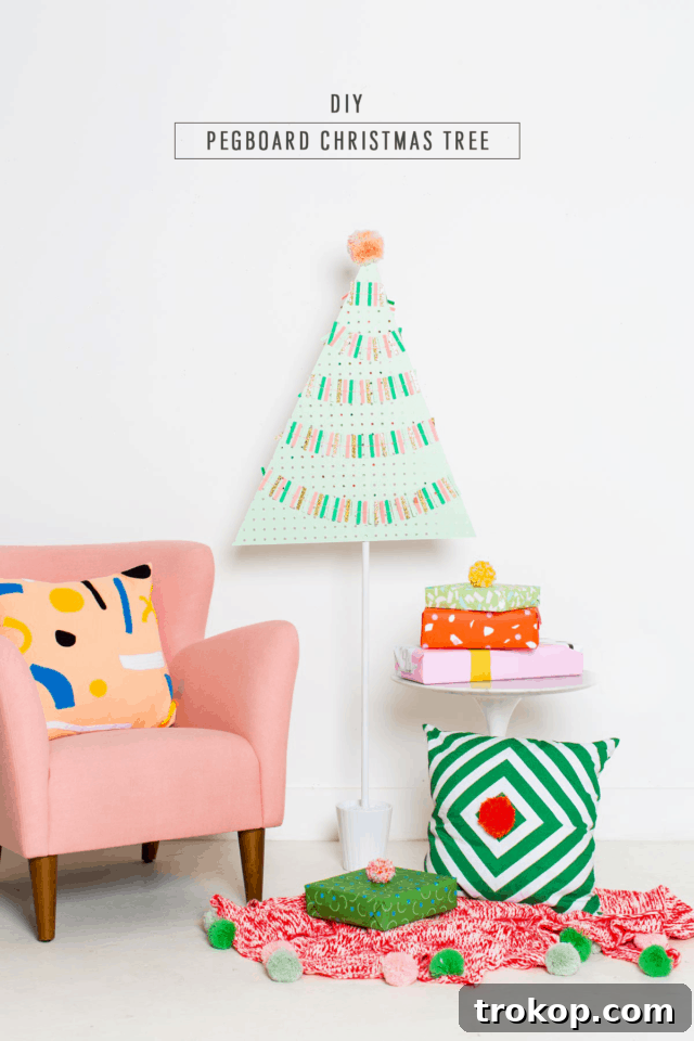 Craft a Modern Pegboard Christmas Tree 9 A beautifully decorated DIY Pegboard Christmas tree adorned with a delicate white garland and a prominent pink pom-pom topper, creating a cheerful holiday display.