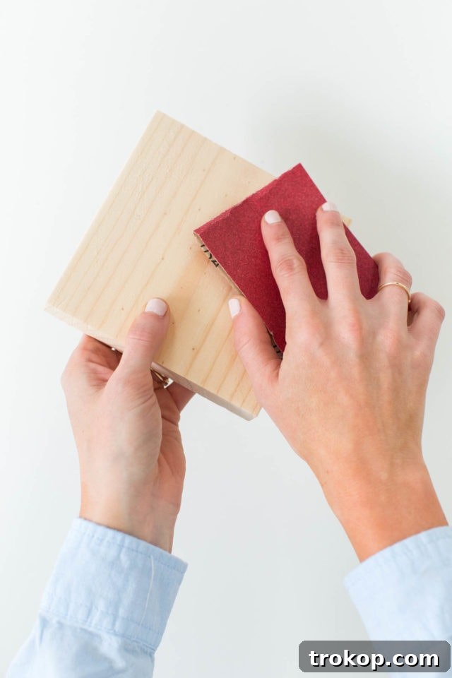 Craft Your Own Flip Photo Book 4 A hand sanding the edges of a wooden block for a DIY project.
