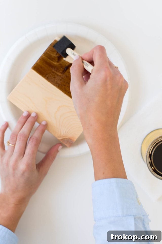 Craft Your Own Flip Photo Book 5 A person applying wood stain to a wooden block with a foam brush.
