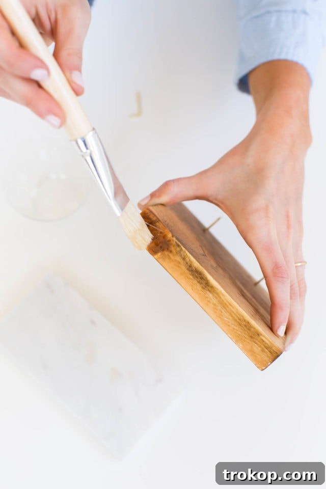 Craft Your Own Flip Photo Book 8 Applying epoxy glue to the bottom of a wooden block before attaching it to a marble tile base.