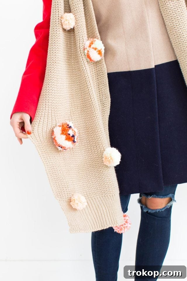 Stylish close-up of a finished DIY Statement Pom Pom Scarf with vibrant pom poms.