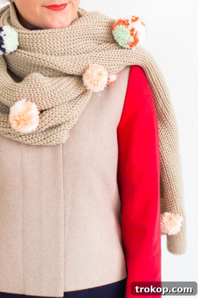 The finished DIY Statement Pom Pom Scarf artfully draped, showcasing its vibrant design.