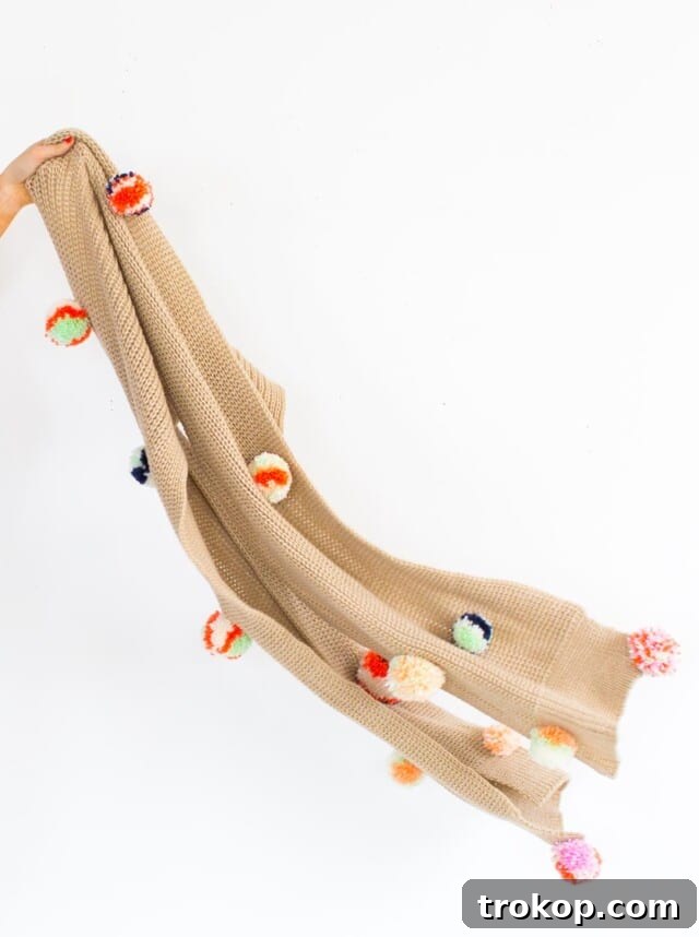 A person wearing a stylish DIY Pom Pom Scarf, showcasing it as a fashionable accessory.