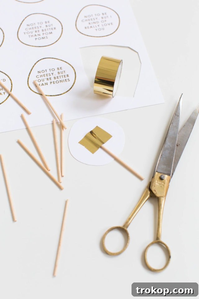 Materials laid out: a pair of scissors, a roll of tape, a handful of toothpicks, and sheets of printed cheese board markers ready for assembly.