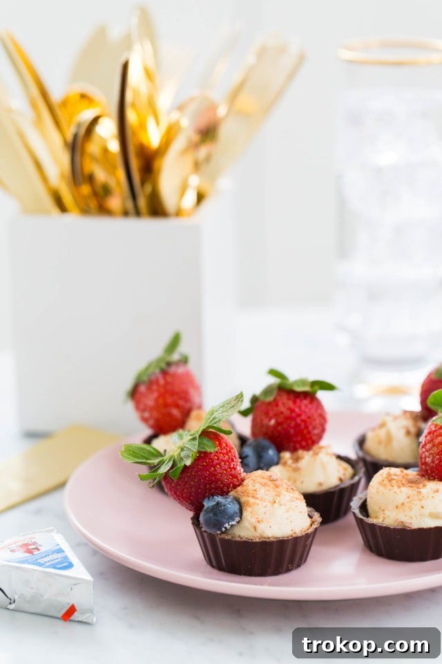 Individual chocolate cups filled with creamy cheese and topped with fresh fruit