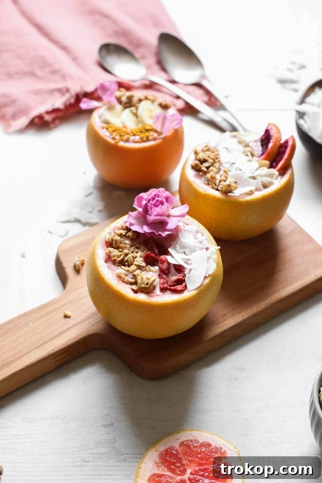 Vibrant Winter Citrus Smoothie artfully presented in a natural grapefruit bowl, adorned with fresh fruit and edible flowers. A truly award-winning DIY blog creation.