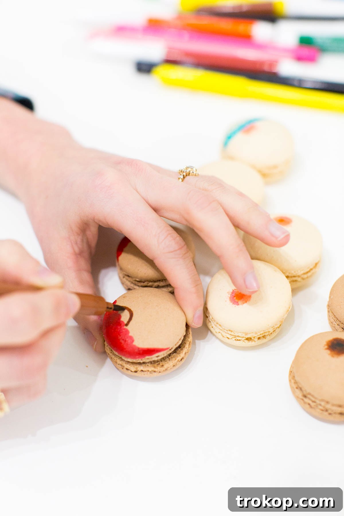 Detailed shot of drawing a bra design onto a macaron with an edible food marker
