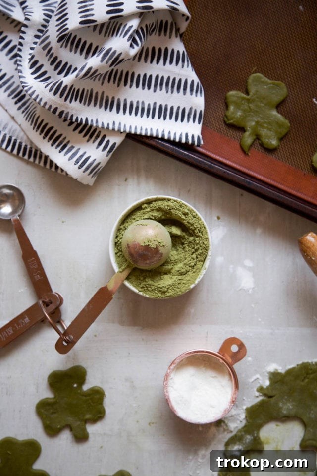 A collection of shamrock matcha cookies on a cooling rack, some dipped in white chocolate