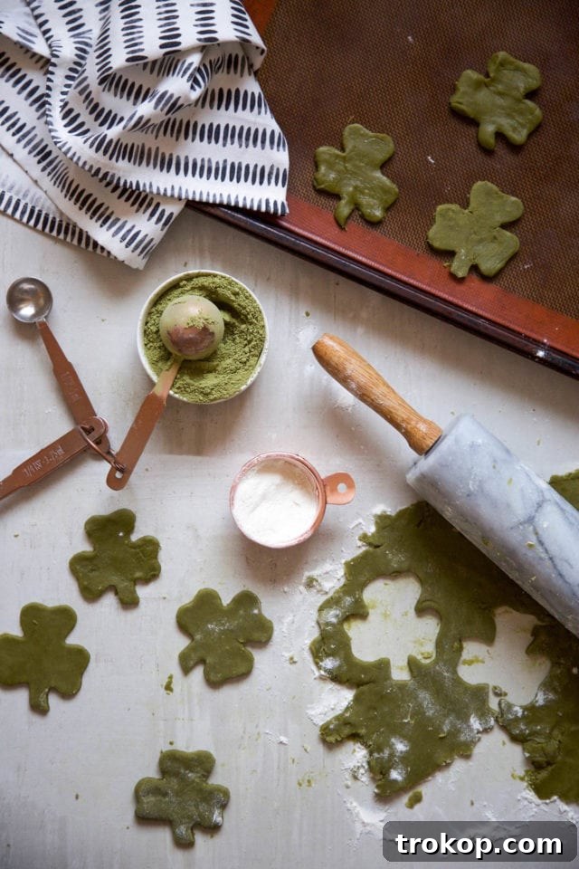 Two hands holding a white chocolate dipped shamrock matcha cookie