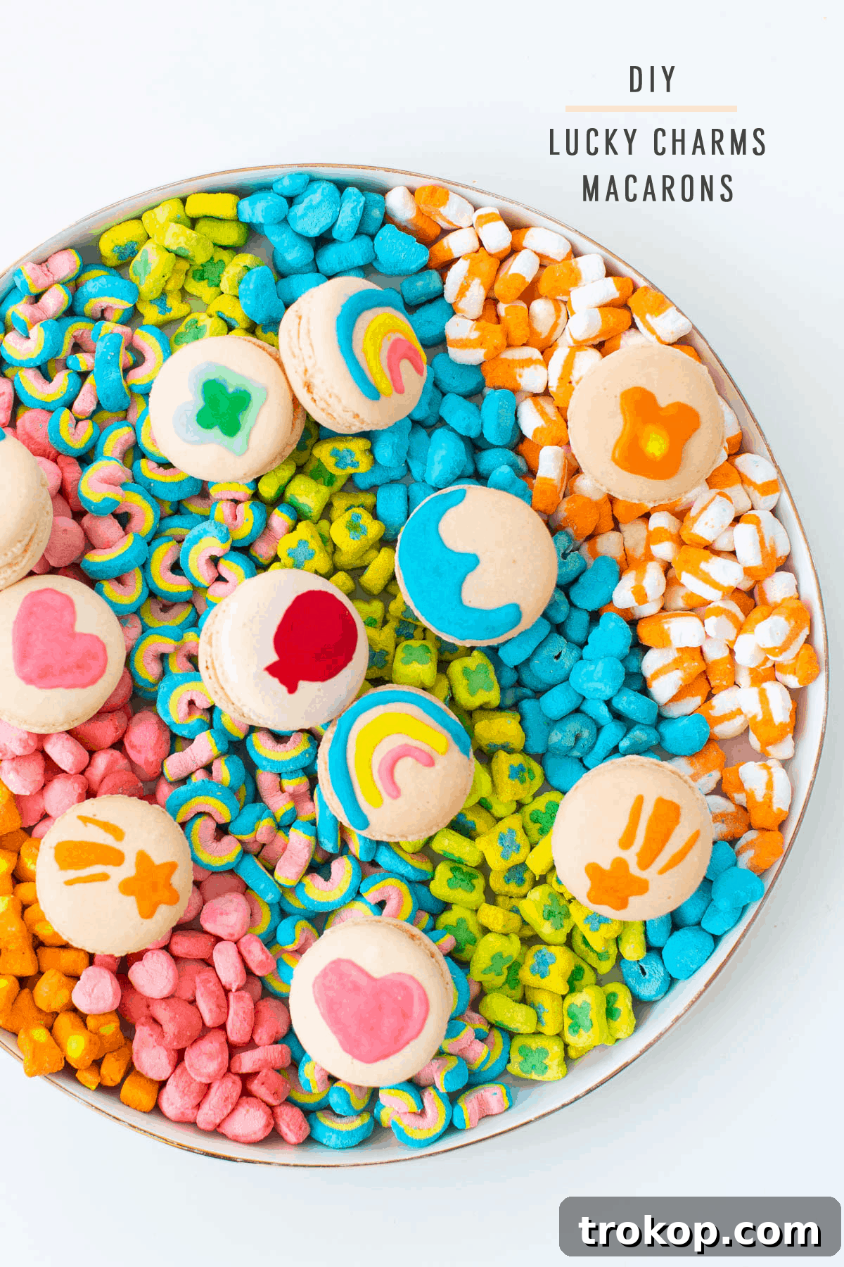 An overhead shot featuring a generous serving of DIY Lucky Charms Macarons, nestled amidst a colorful assortment of Lucky Charms marshmallows, creating an inviting and magical display.