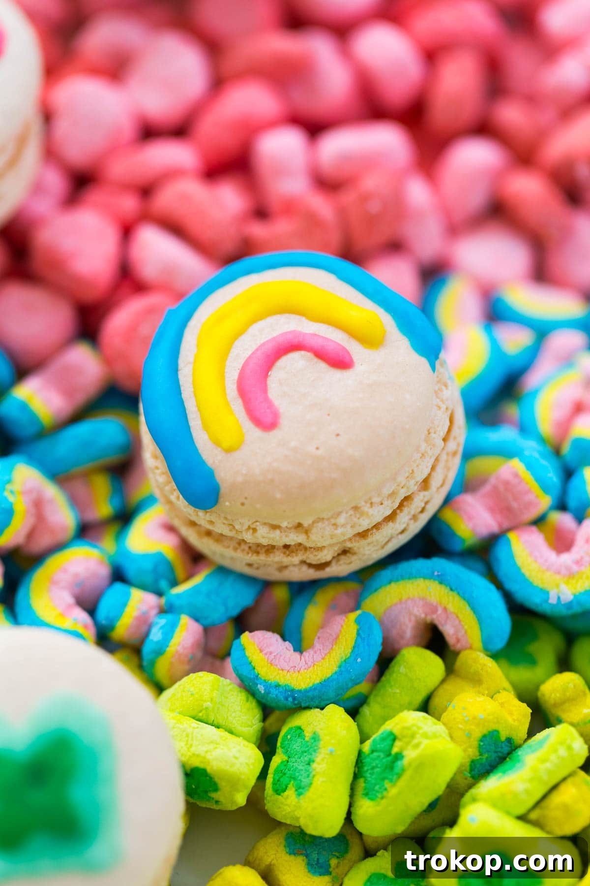 An assortment of macaron shells with various Lucky Charms designs painted on them, showing the progress of decorating.