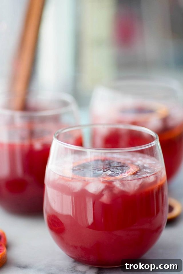 Vibrant Blood Orange Sangria 4 A pitcher of Blood Orange Sangria being poured into a glass, garnished with fresh blood orange slices.