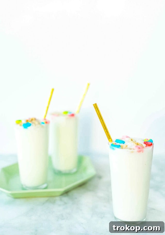 Two glasses of Boozy Cereal Milk Egg Cream garnished with Lucky Charms marshmallows, ready for a festive celebration.