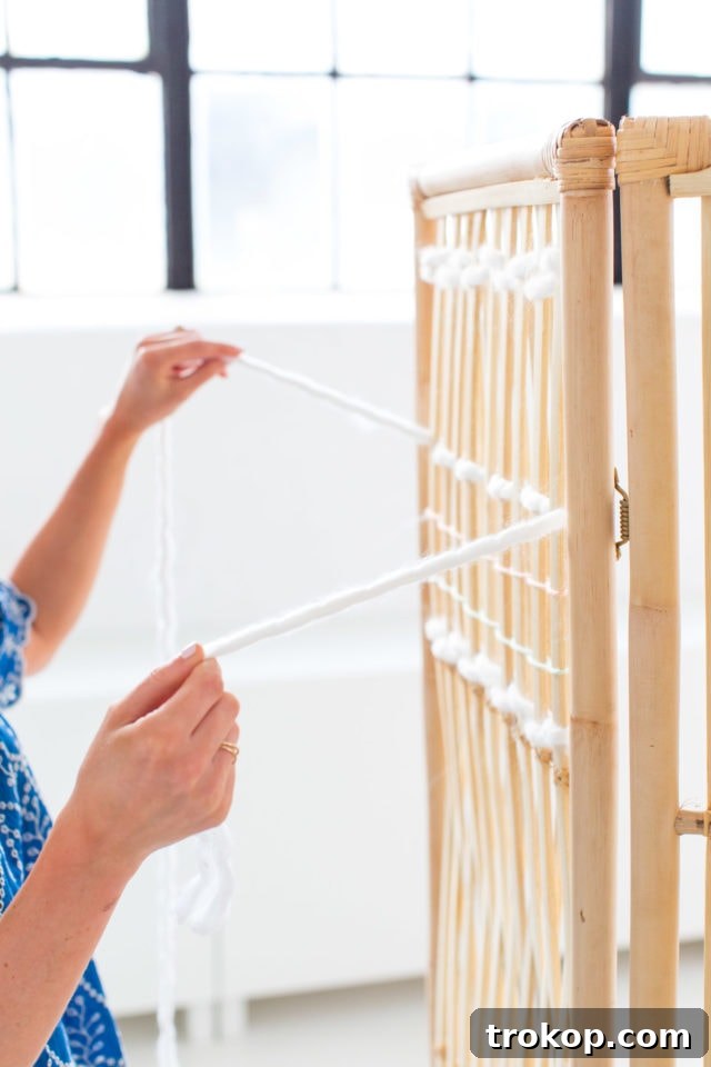 Weave Your Own Room Divider 4 Materials and tools laid out for the DIY Ikea Hack Woven Room Divider project, including yarn and scissors next to a rattan screen.