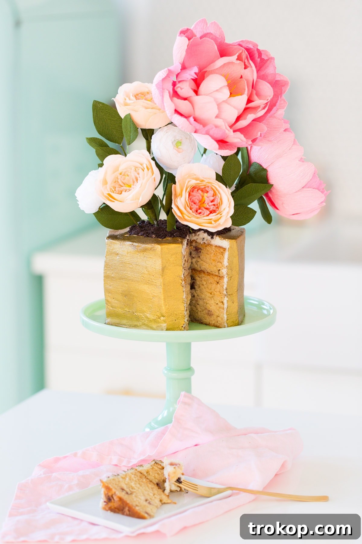 Sweet Flower Pot Cake Secrets 13 An elegantly decorated flower pot cake, featuring a hexagonally carved cake base adorned with edible gold luster and vibrant crepe paper flowers, set against a bright, airy background, perfect for a modern Easter celebration.