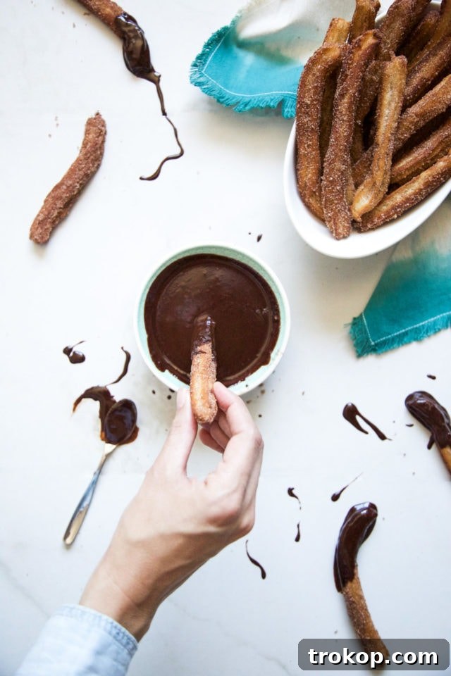 A basket full of golden-brown cinnamon sugar-coated churros, piled high and ready to be enjoyed.
