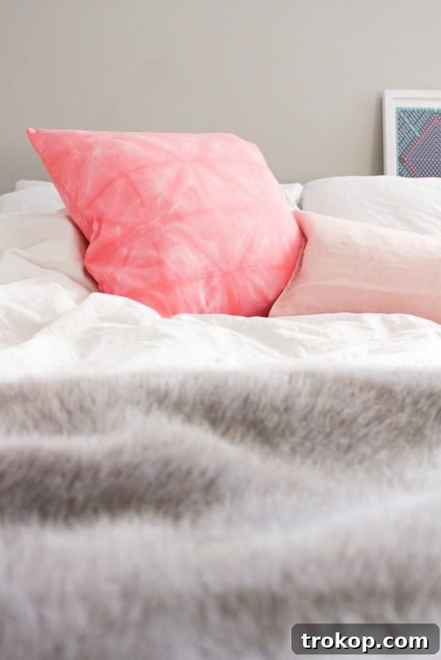 Craft Your Own Shibori Tie Dye Pillow 3 Close-up of a beautifully patterned pink Shibori throw pillow, showcasing the intricate folds and dye resist patterns